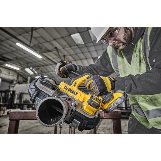Worker using 18V XR Band Saw to cut thick metal pipe